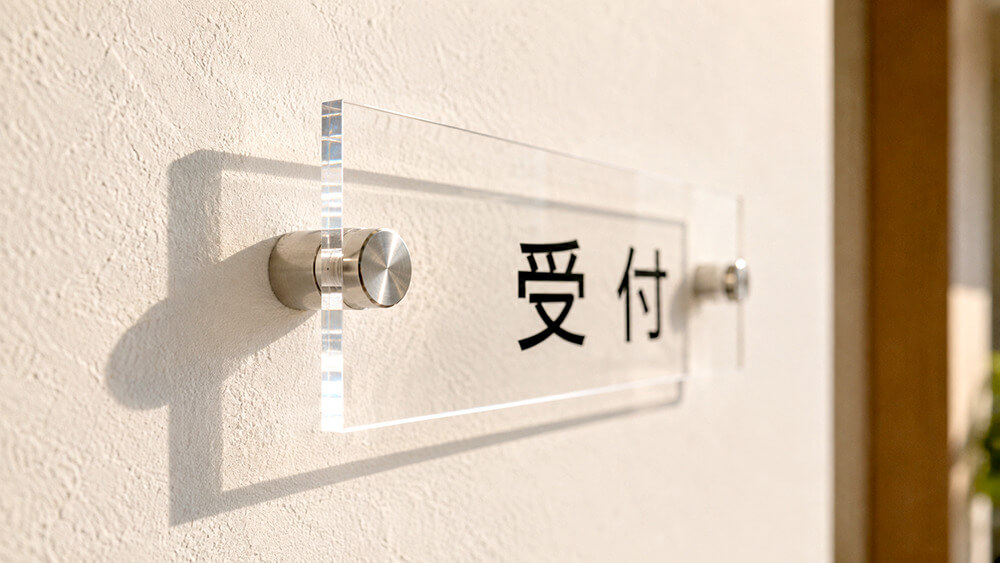 化粧ビスで壁から浮かせて取り付けたアクリル看板と、壁に落ちる影