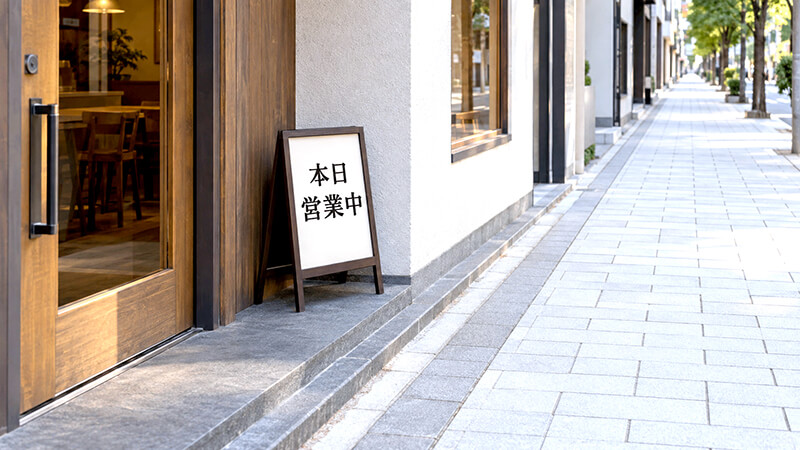 歩道にはみ出して置かれたA型看板と、敷地内に納めて置かれた看板の対比
